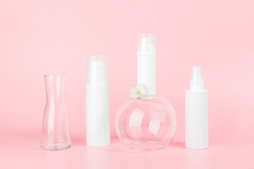 Set of care cosmetic for skin, face, body or hair. White blank cosmetics bottles and tube on glass podiums, pink background. Spa Cosmetic Beauty Concept. Front view Mockup