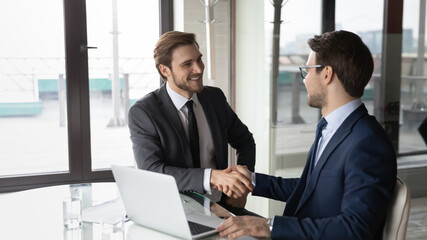 Wide banner view of smiling businessmen shake hands close deal make agreement after successful...