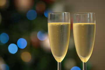Champagne glasses over holiday bokeh blinking background, rotating on turntable, glasses with sparkling wine, celebration, party. High quality 4k footage