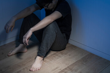 暗い部屋で床に座っている男性