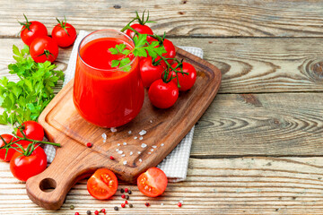  Glass of fresh tomato juice and tomatoes on the wooden background, free space for your text