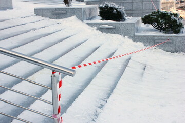 the stairs are covered In ice after an icy rain. Ice-slick steps. Protective tape near the slippery ice stairs. Winter has come. cleaning of city stairs from ice and snow.