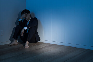 暗い部屋で床に座り込んだビジネスマン