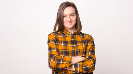 Confident pretty woman is smiling at the camera with arms crossed over white background.