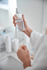 Focused image of beautiful woman hand with bottle in hand in room indoors