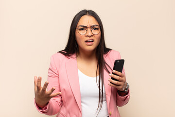 young latin woman looking angry, annoyed and frustrated screaming wtf or what’s wrong with you