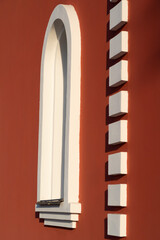 White narrow window on the red stone wall of the temple, background