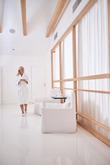 Charming elegant adult woman in white bathrobe spending time in cosmetology clinic