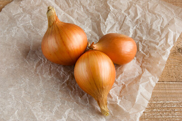 unpeeled ripe onions on a light wooden background