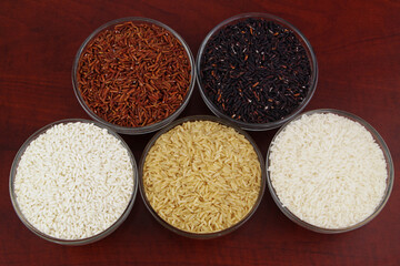 Assortment of rice in glass bowls close up - white, brown, red and black rice.