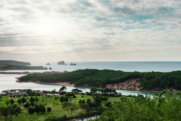 Fototapeta na wymiar green coastline at sea with golf course and cloudy sky