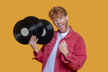 Red-haired bearded young man in red jacket with a record feeling awesome
