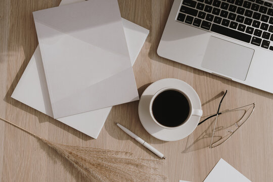 Flatlay of coffee cup, laptop, pampas grass, notebook on wooden table. Flat lay, top view morning breakfast and work concept.