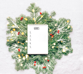 Blank notebook for planning goals on New Year's green branches with lights