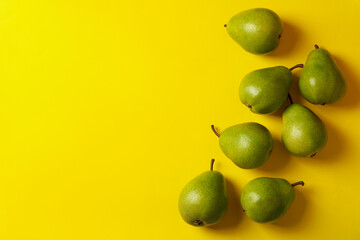 Fresh green pears on yellow background, top view