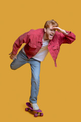 Fototapeta premium Ginger young man in red jacket with a skateboard