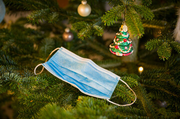 Christmas 2020: Respirator mouth nose cover hanging in decorated Christmas tree during Covid-19...