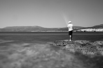 Urla, Izmir, Turkey; A child is fishing on the Altınköy cliffs, there is a flurry of movement due to the long exposure. 11 July 2020
