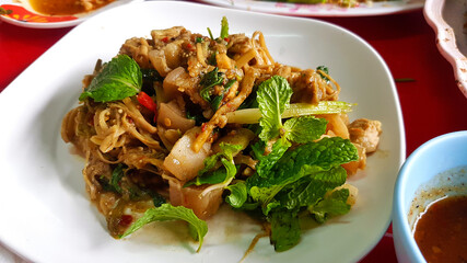 Close up spicy preserved sliced bamboo shoot and pork belly in white dish or plate at street food. Famous local meal in Thailand