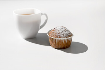 Morning breakfast with cupcake. Cup of tea and muffin on a white table.