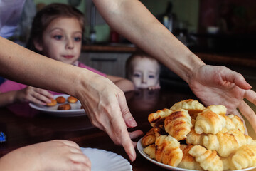 Obraz na płótnie Canvas The woman takes out the finished cookies from the oven, and the children watch with interest. Close-up - a baking sheet with ready-made pastries. The concept of spending time during quarantine
