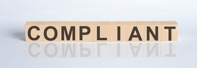 COMPLIANT word from wooden blocks on the white desk