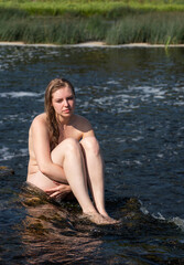 Beautiful young nude woman enjoying summertime in waterfall