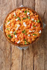 Greek scrambled eggs with tomatoes and feta cheese close-up in a plate on the table. vertical top view from above