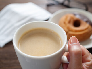 マスクを外し、コーヒーを飲む女性の手元