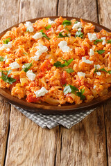 Greek scrambled eggs with tomatoes and feta cheese close-up in a plate on the table. vertical