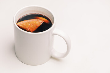 Mug with mulled hot wine with orange on the white background.
