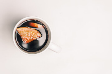 Top view on the white cup with hot wine or punch on the black background with copy space