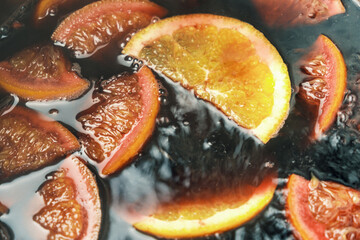 Making of mulled wine or punch with slices of orange, anise slice, cinnamon and clove.