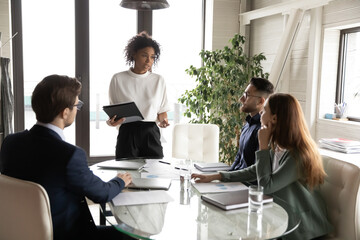 Confident young African American businesswoman stand lead head meeting with multiracial colleagues...