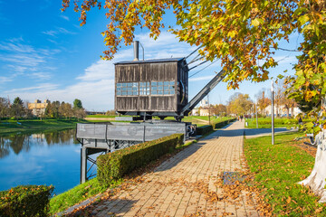 Promenade and old steam crane on the river Kupa in Sisak, Croatia, autumn day