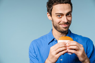 Joyful handsome guy smiling while posing with hamburger