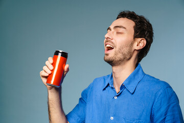 Happy handsome guy drinking soda with eyes closed - obrazy, fototapety, plakaty