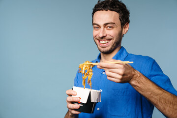 Joyful handsome guy smiling while eating asian noodles takeaway