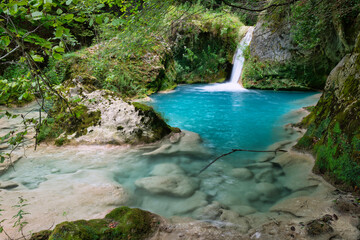 small river of turquoise water with a waterfall that ends in a pond