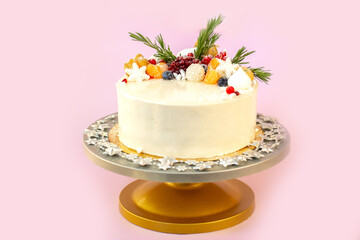 New Year's festive Christmas cake on a stand on a pink background. Christmas sweets decorated with New Year's decor and berries.