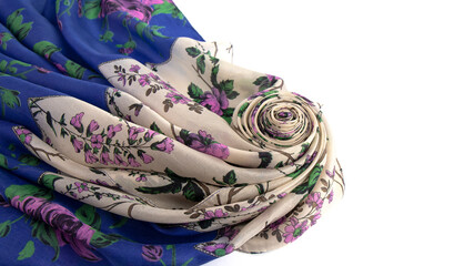 A light blue and white silk scarf with a floral pattern is beautifully folded in waves on a white background. 