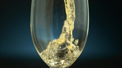 Clouse-up of a transparent glass with a drink pouring in it on a dark blue background in slow motion, 1000fps