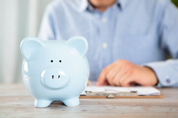 Piggy bank on the table and the male behind