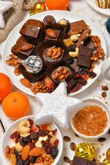 Obraz na płótnie Canvas sweet food top view background for merry christmas or new year holiday decoration - chocolate candies, tangerines, cookies on white wood