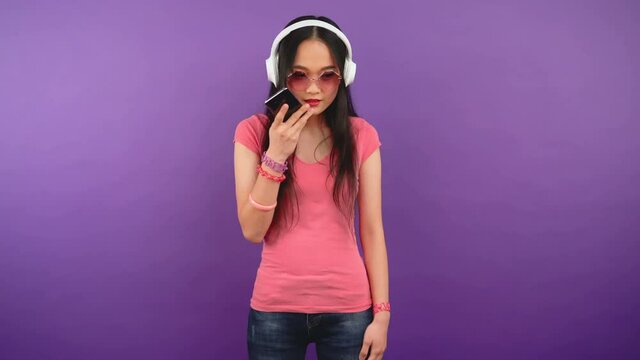 Young Asian woman over isolated purple background sending voice message. 4K