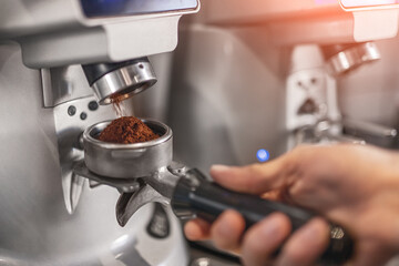 Crop barista grinding coffee in cafe