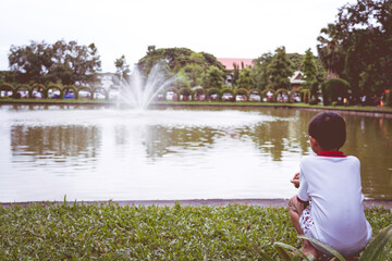 Fototapeta premium A little boy sitting on the edge of the pool, sad concept.