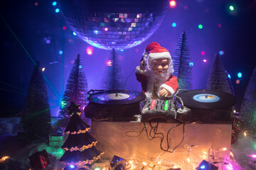 Dj mixer with headphones on dark nightclub background with Christmas tree New Year Eve. Close up view of New Year elements on a Dj table. Holiday party concept. Empty space