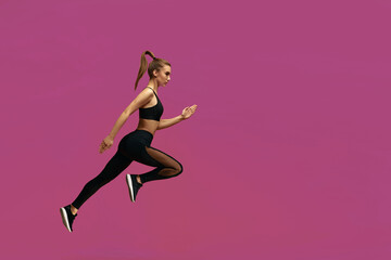 Fototapeta na wymiar athletic beautiful woman in black sportswear running over yellow background. fit girl jumping. sport and fitness concept. copy space