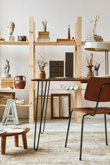 Unique artist workspace interior with stylish desk, wooden easel, bookcase, artworks, painting accessories, decoration and elegant personal stuff. Modern work room for artist. Template.